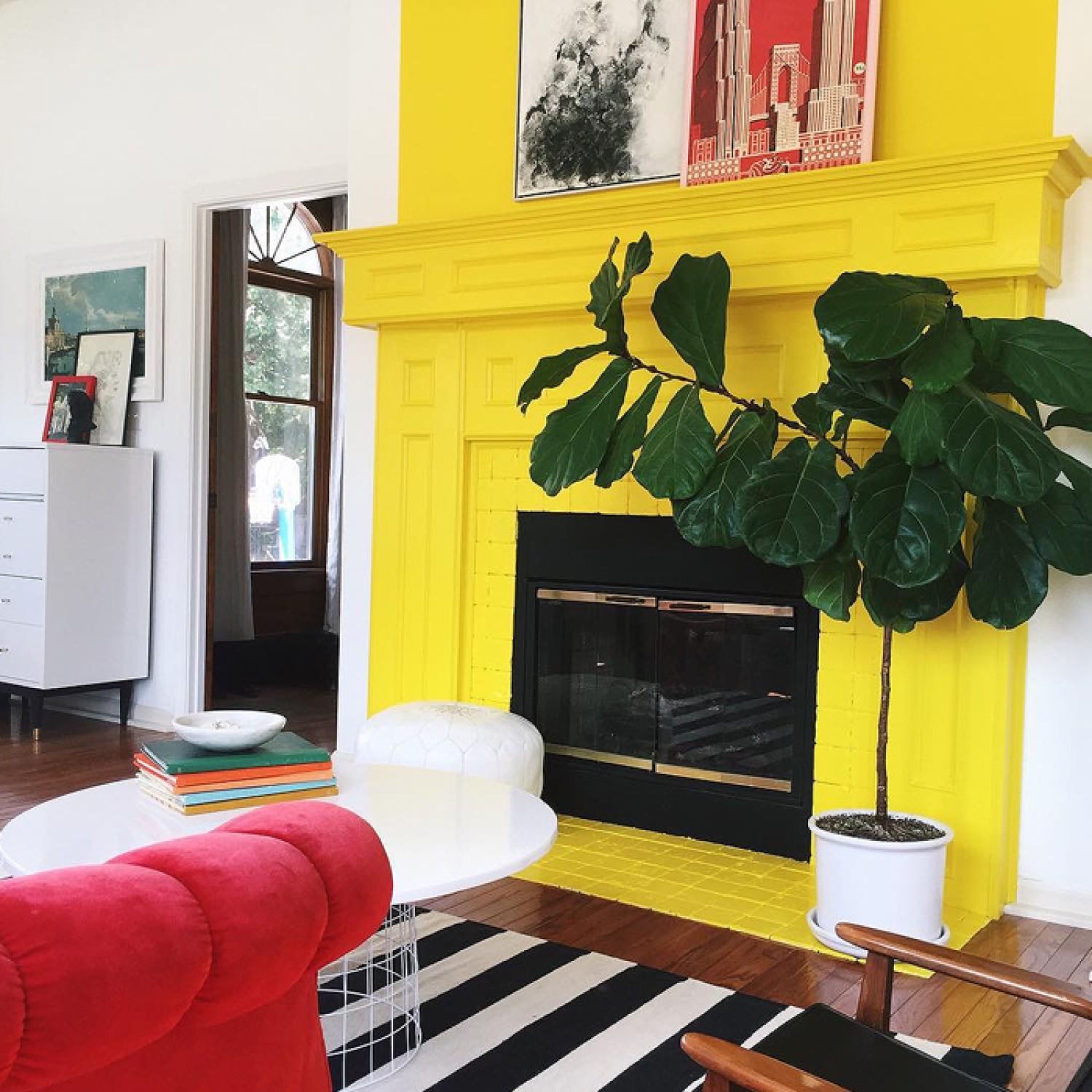 A bright yellow painted fireplace with fiddle leaf fig