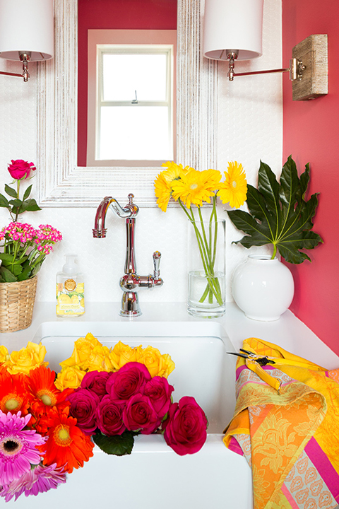 A hot pink painted bathroom with flowers in the sink