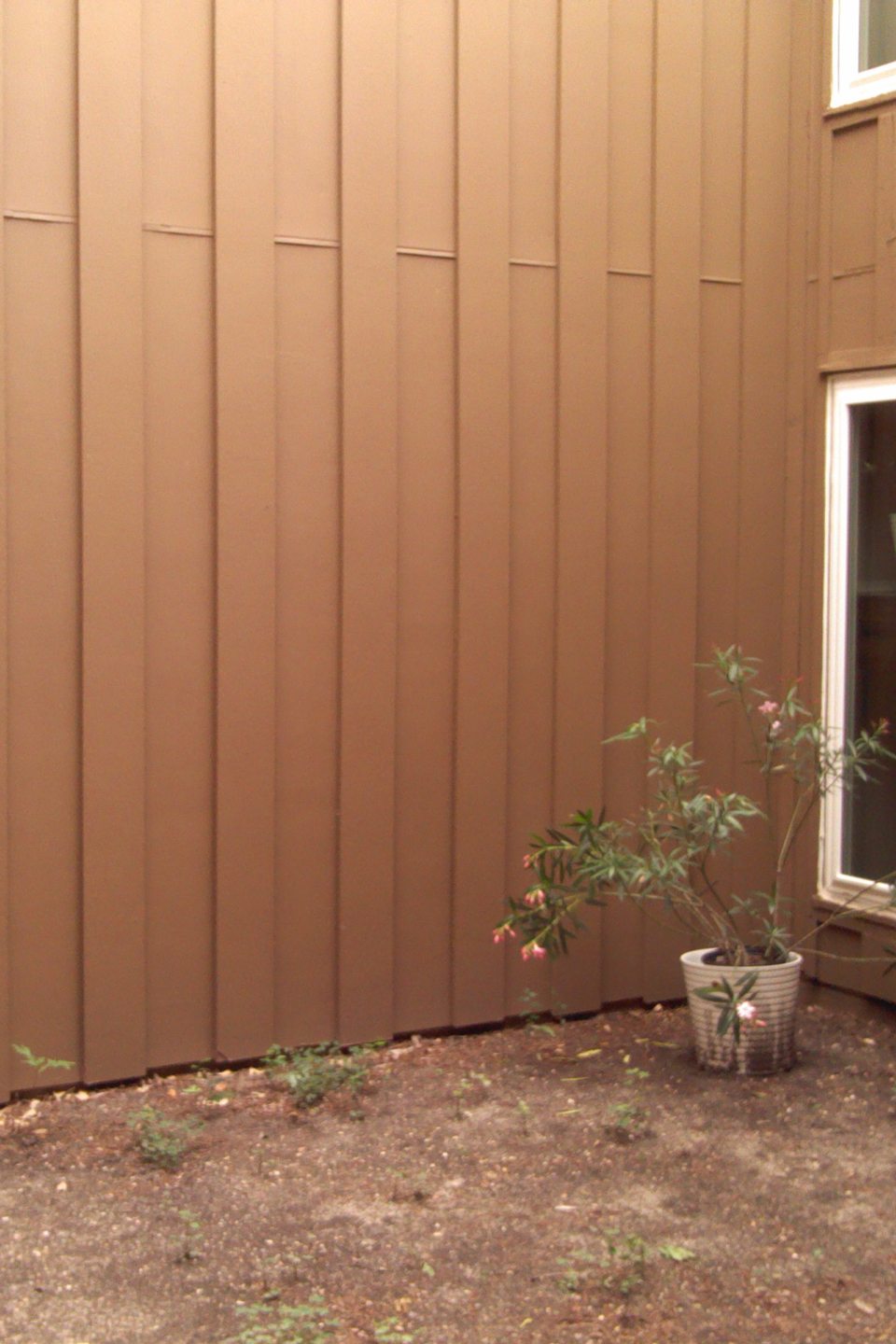 A before image of a small yard with a dirt patch