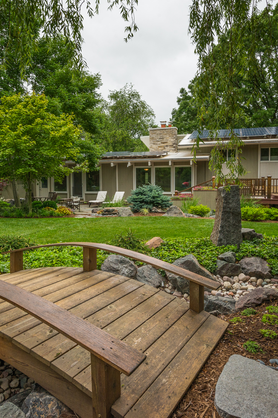 An after image of a redesigned zen garden with wood bridge