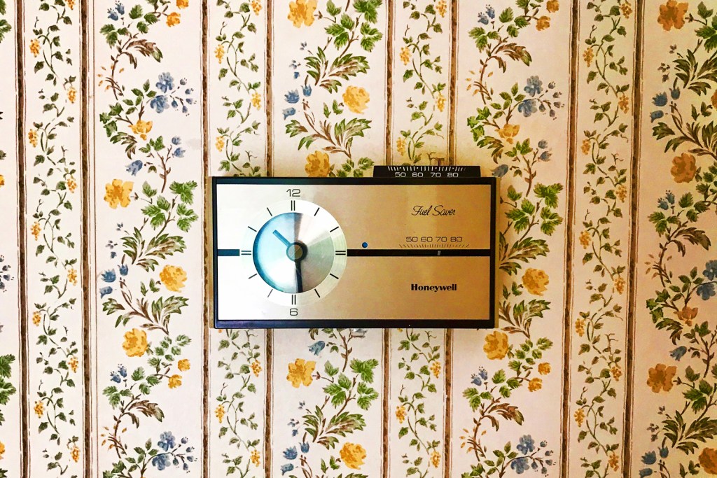Vintage wallpaper with outdated thermostat in a home