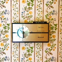 Vintage wallpaper with outdated thermostat in a home