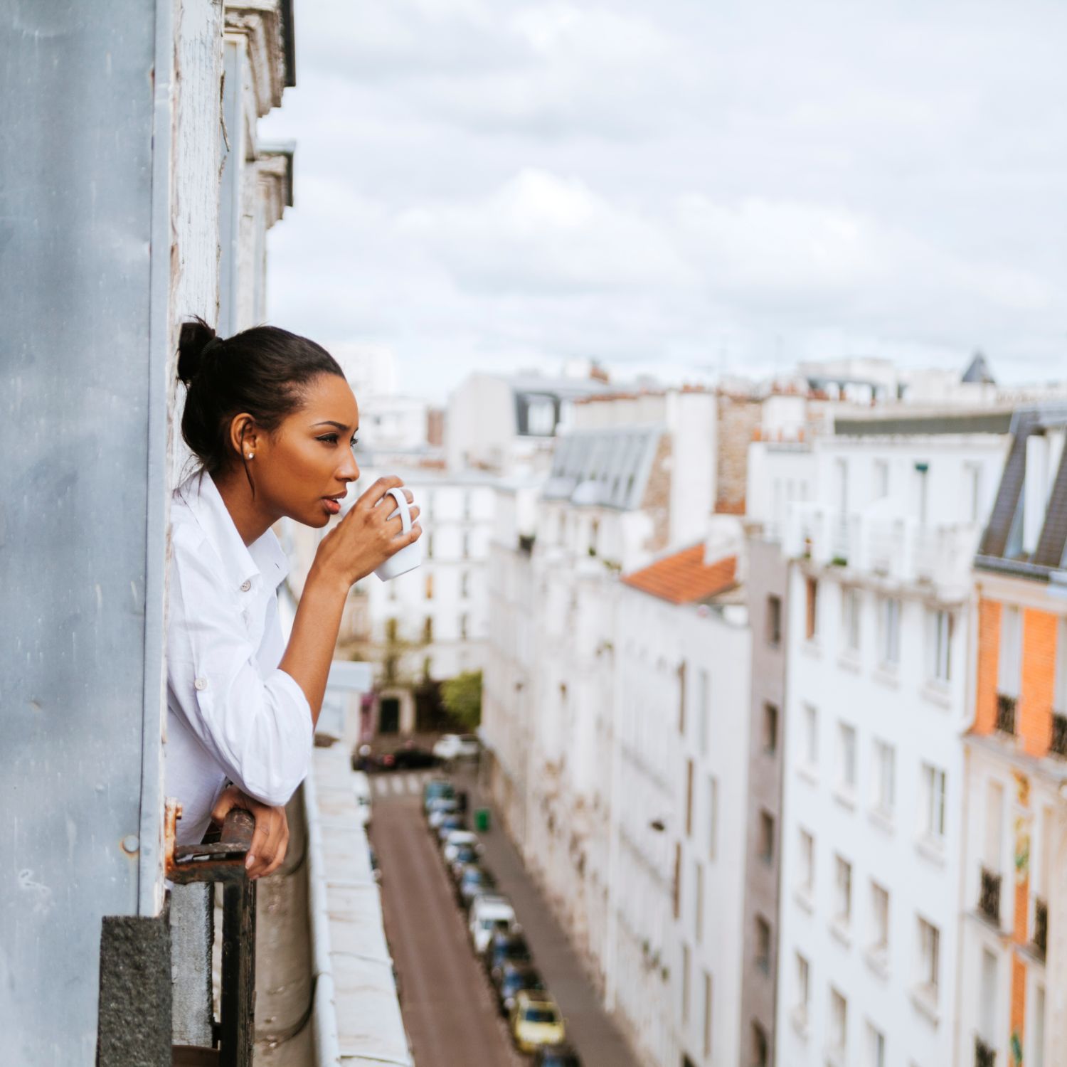 French woman drinking coffee looking out of her window