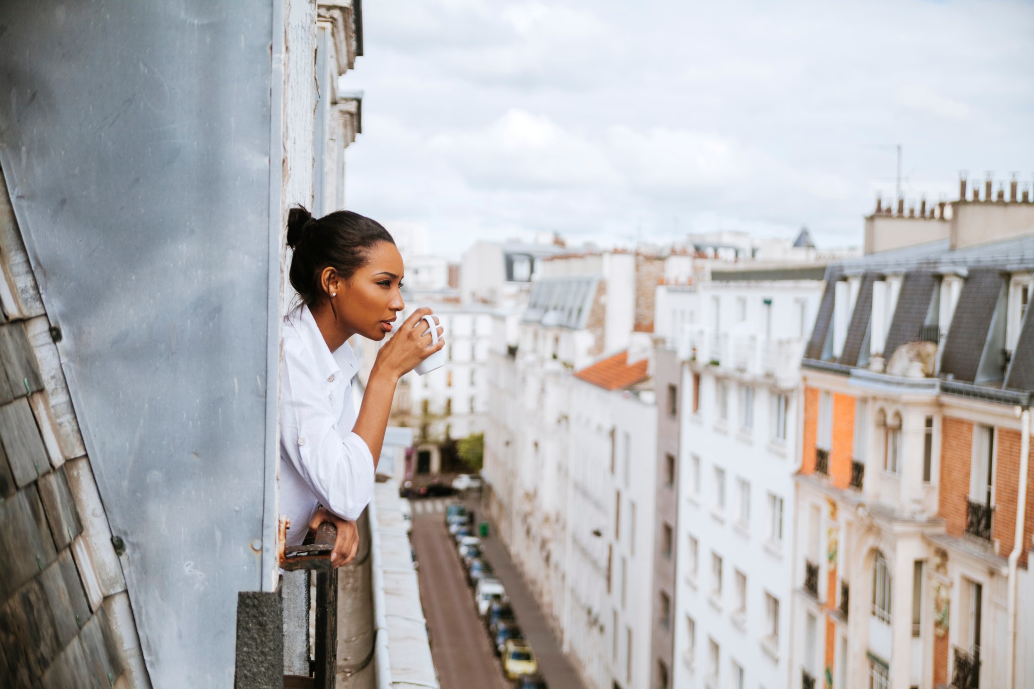 French woman drinking coffee looking out of her window