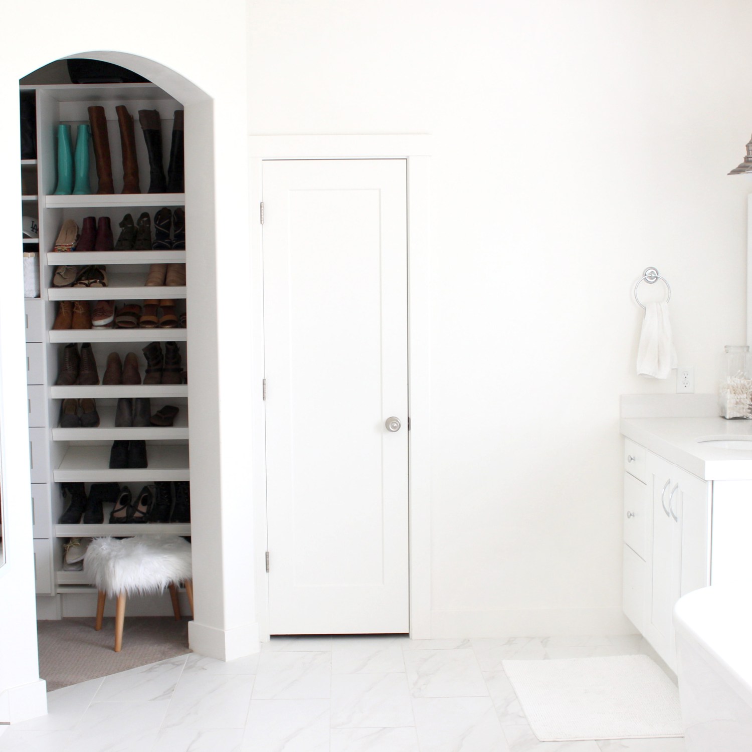 All white bathroom with glimpse of a shoe closet