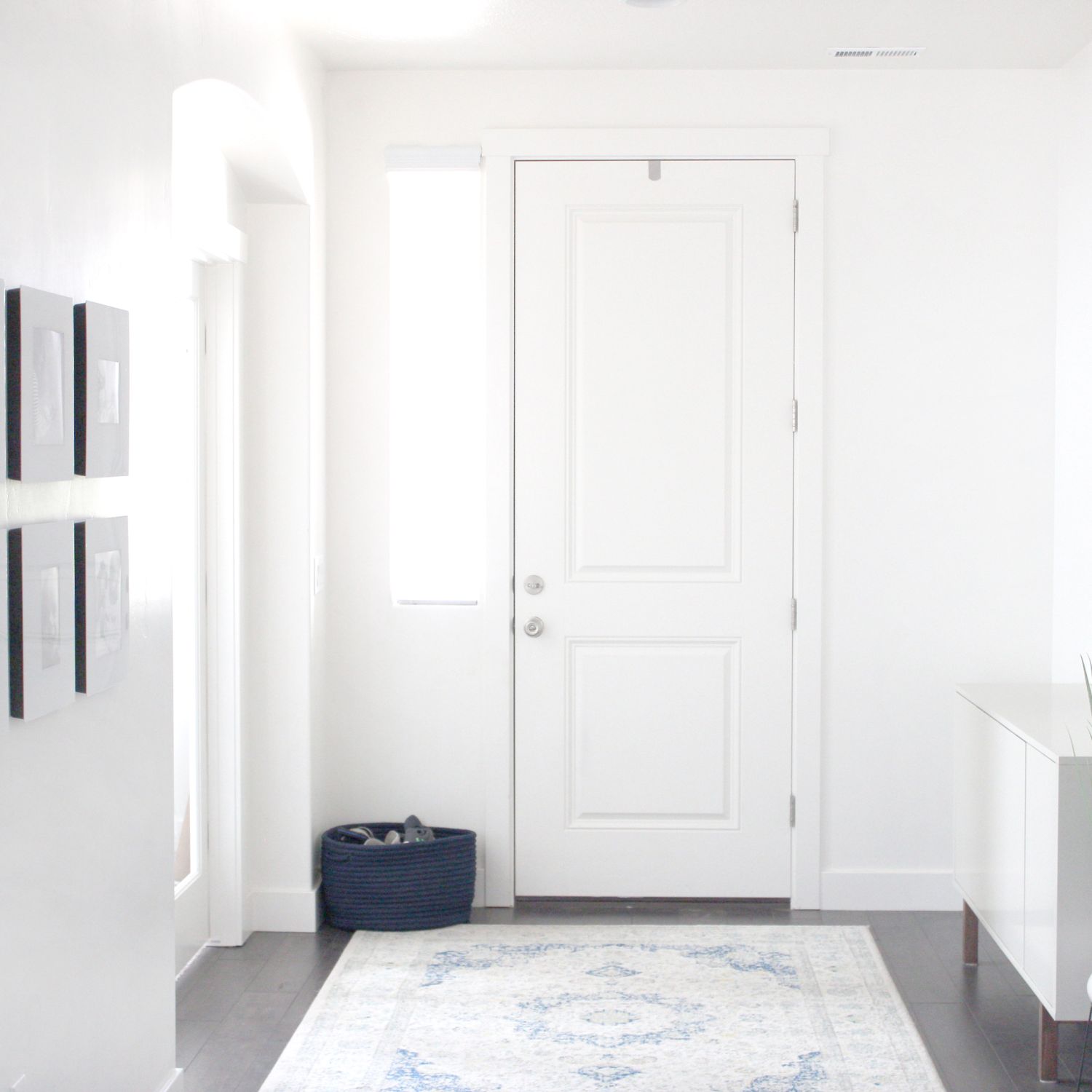White entryway with pictures along one wall and white rug