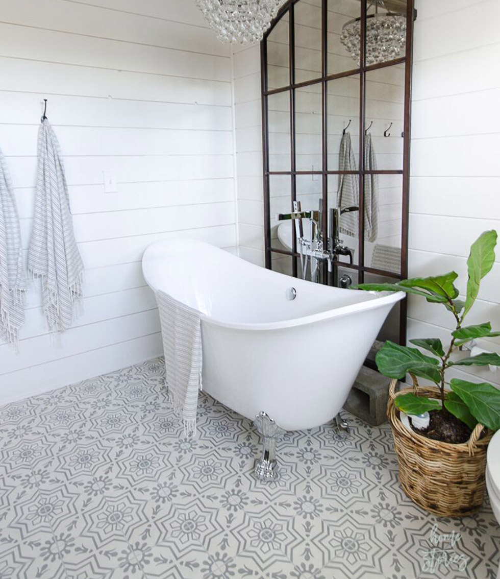 Patterned tile in bathroom with white tub and chandelier