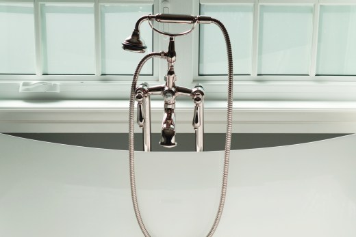 Close up of removable shower head resting on cradle in tub