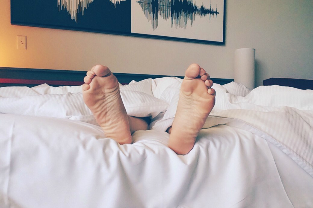 Pair of feet sticking out from white bedsheets