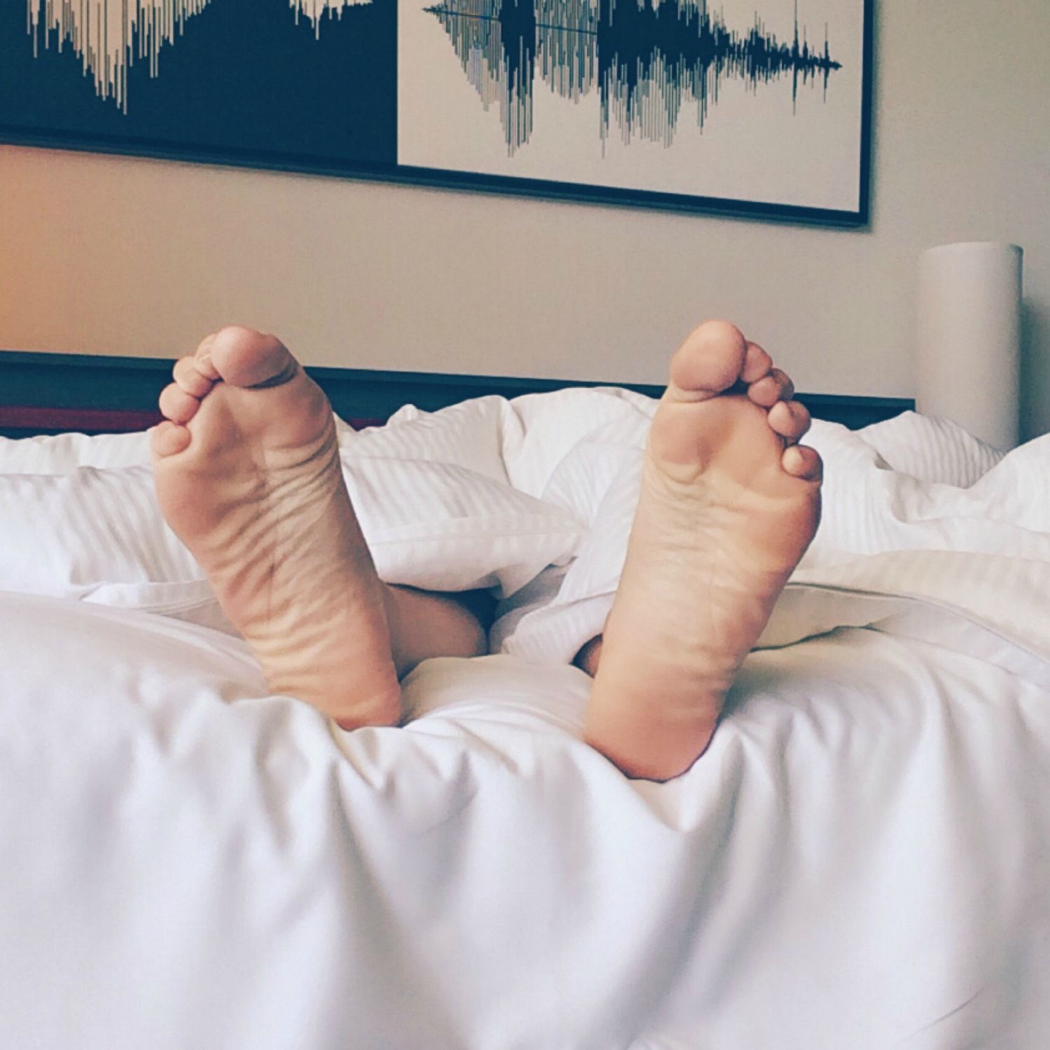 Pair of feet sticking out from white bedsheets