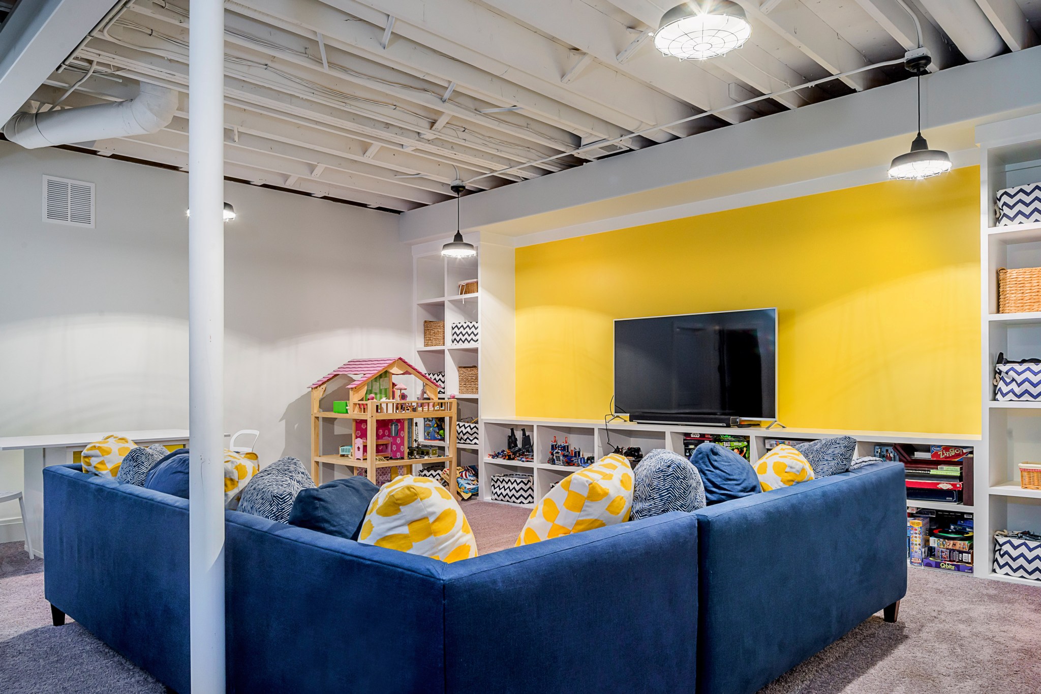 Blue and yellow basement with built-in shelves, open ceiling