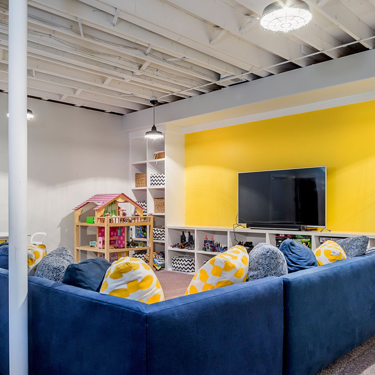 Blue and yellow basement with built-in shelves, open ceiling