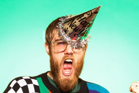 Bearded man in ugly sweater with New Year's party hat