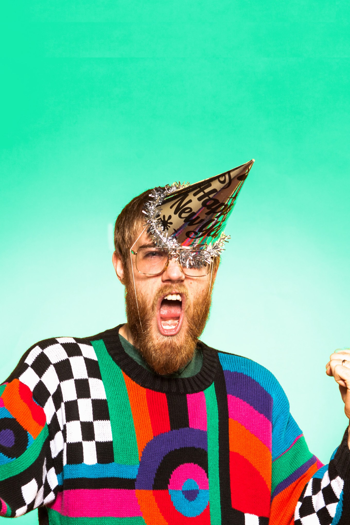 Bearded man in ugly sweater with New Year's party hat