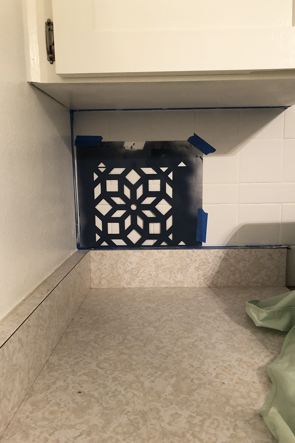 White tile with stencil taped to it for DIY tile upgrade
