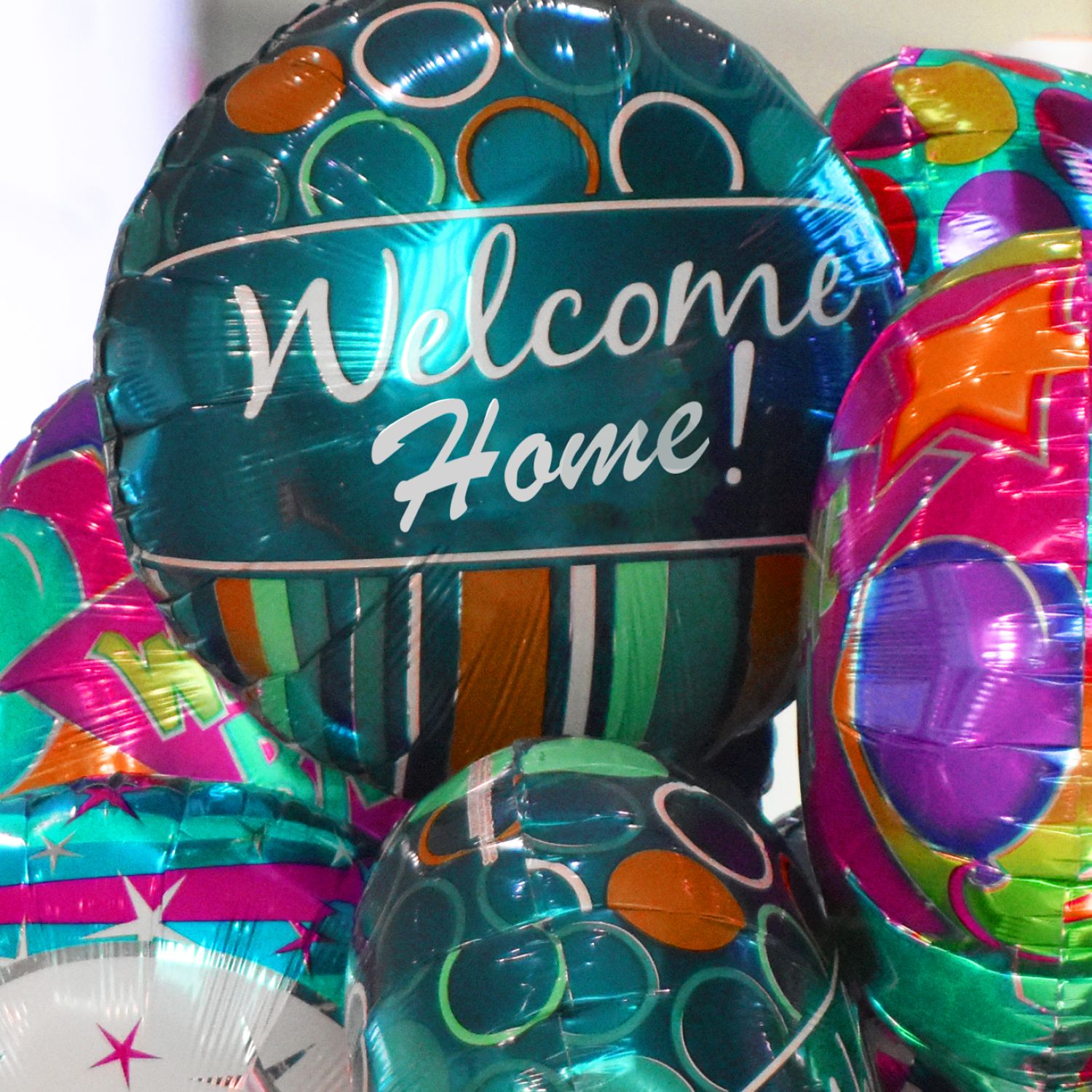 Assortment of foil balloons that say, "Welcome home!"
