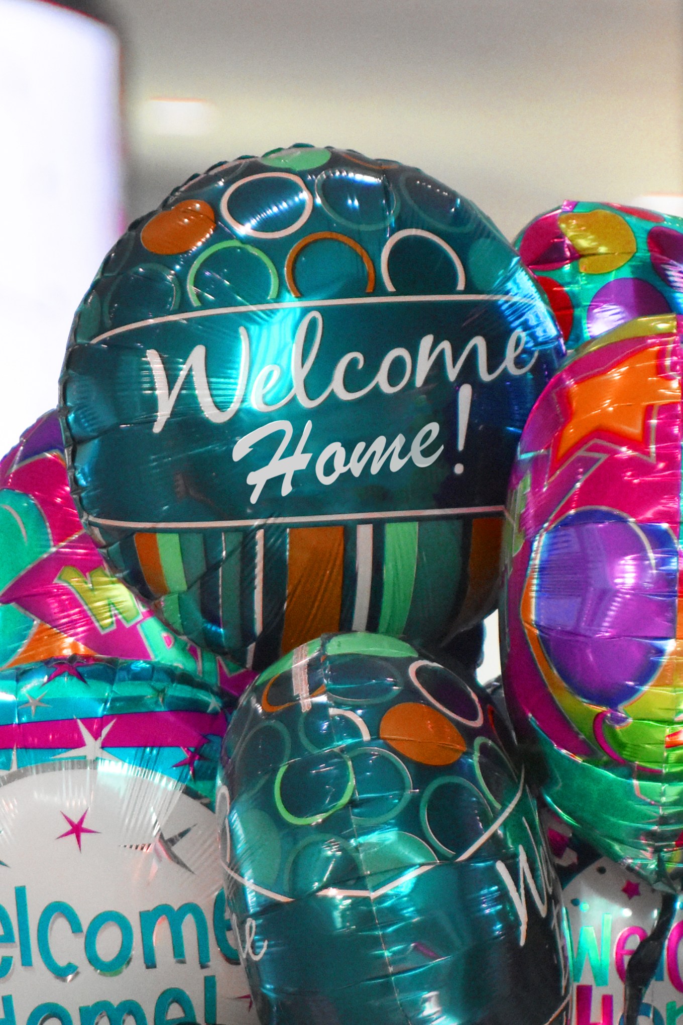 Assortment of foil balloons that say, "Welcome home!"
