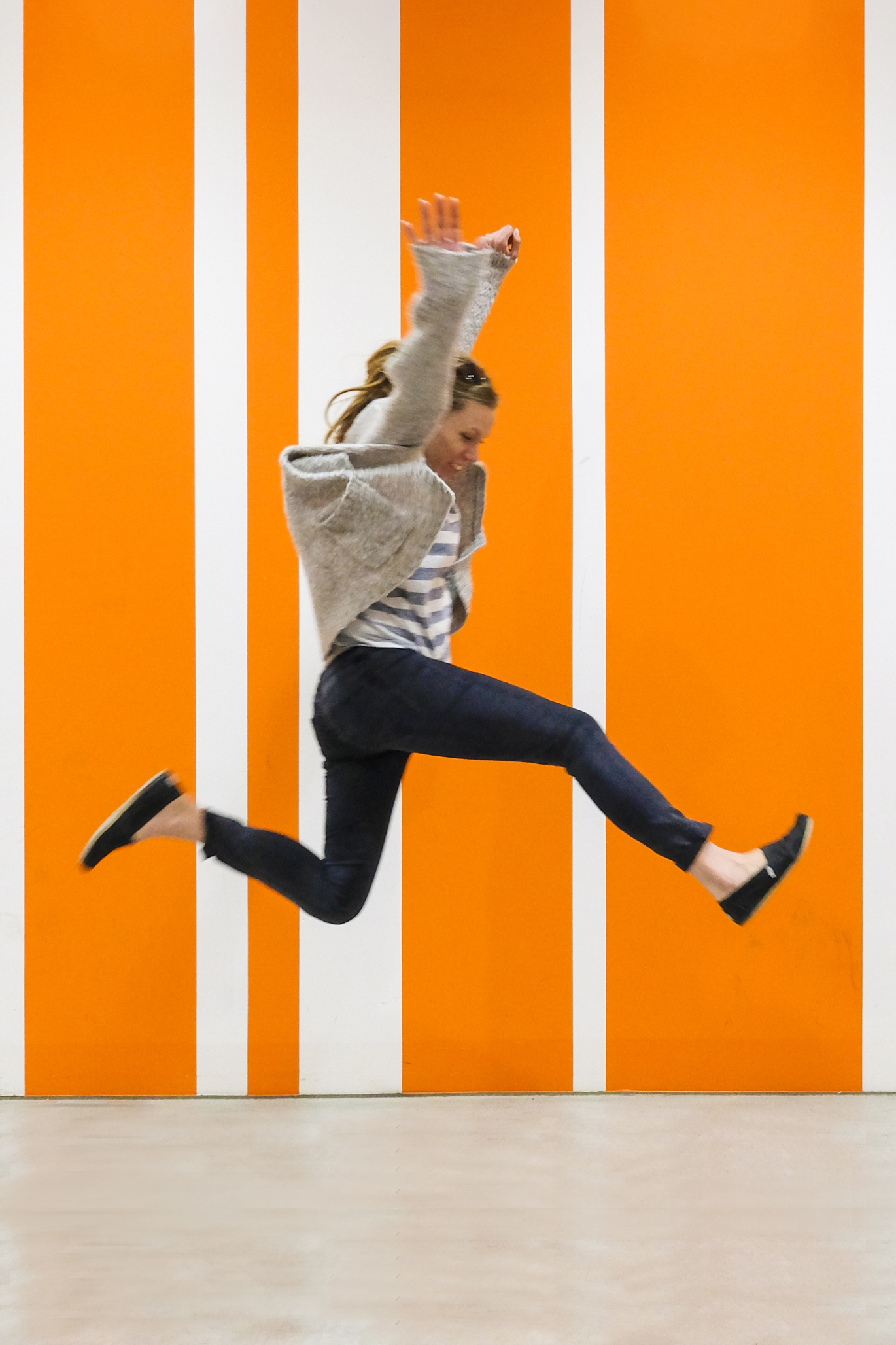 Woman jumping for joy against orange striped background