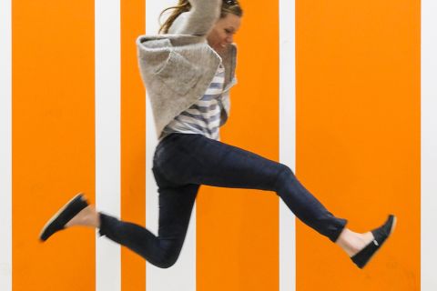 Woman jumping for joy against orange striped background