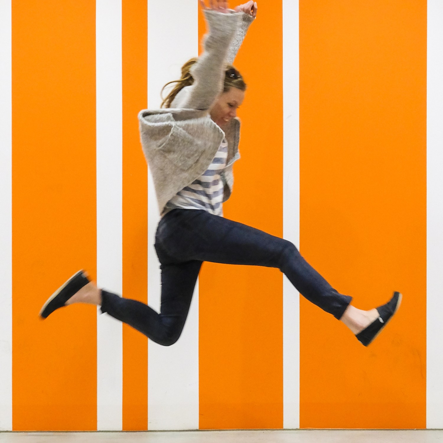 Woman jumping for joy against orange striped background