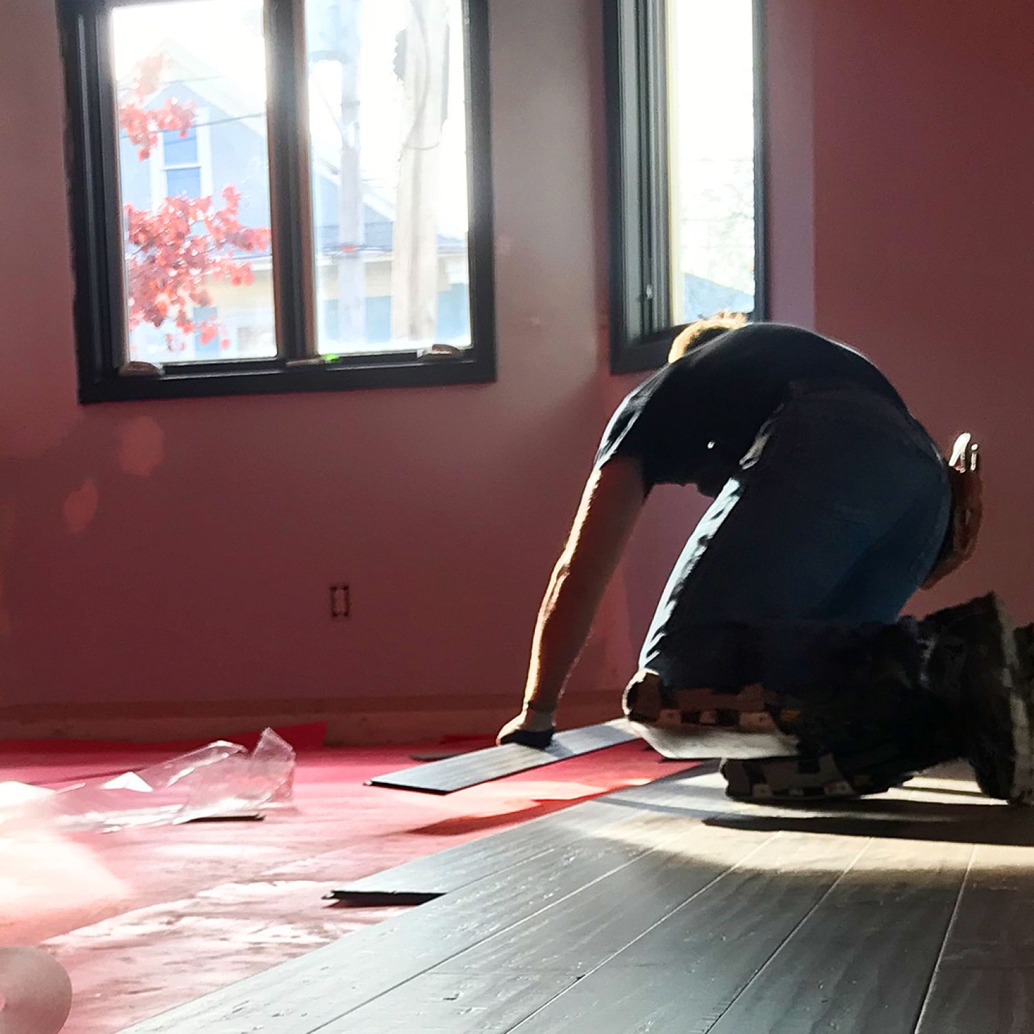 Man on hands and knees laying boards for wood floor