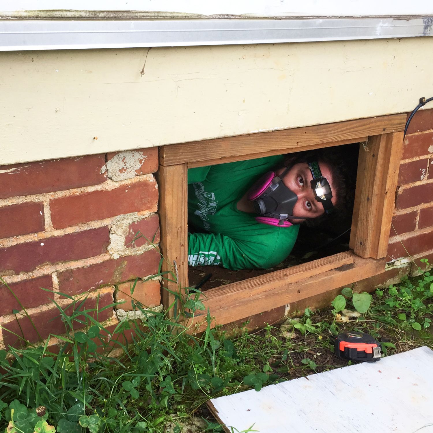 Man with respirator mask on peering out from basement window