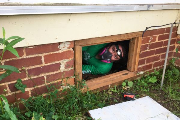 Man with respirator mask on peering out from basement window