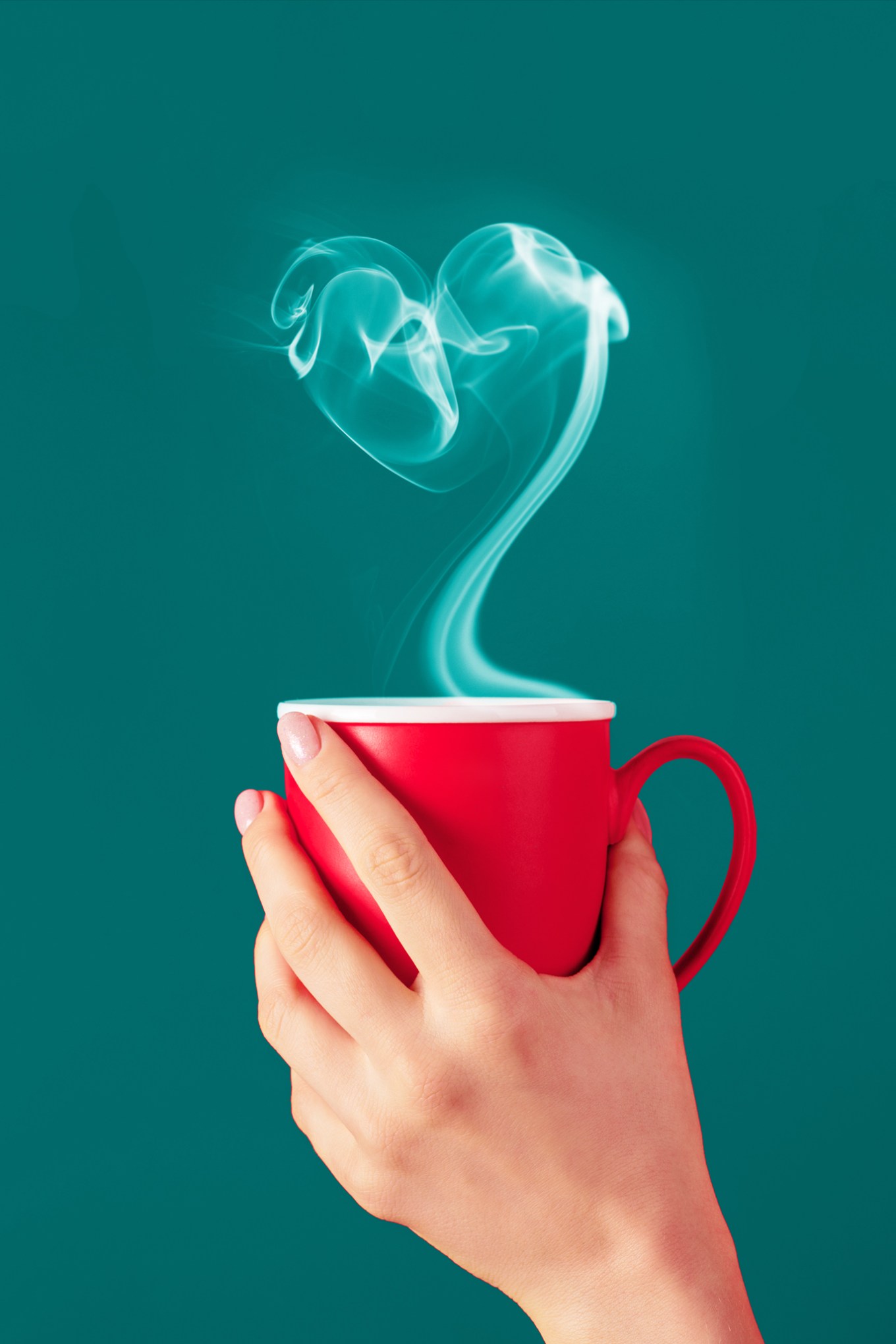 Hand holding red mug with heart-shaped smoke from beverage