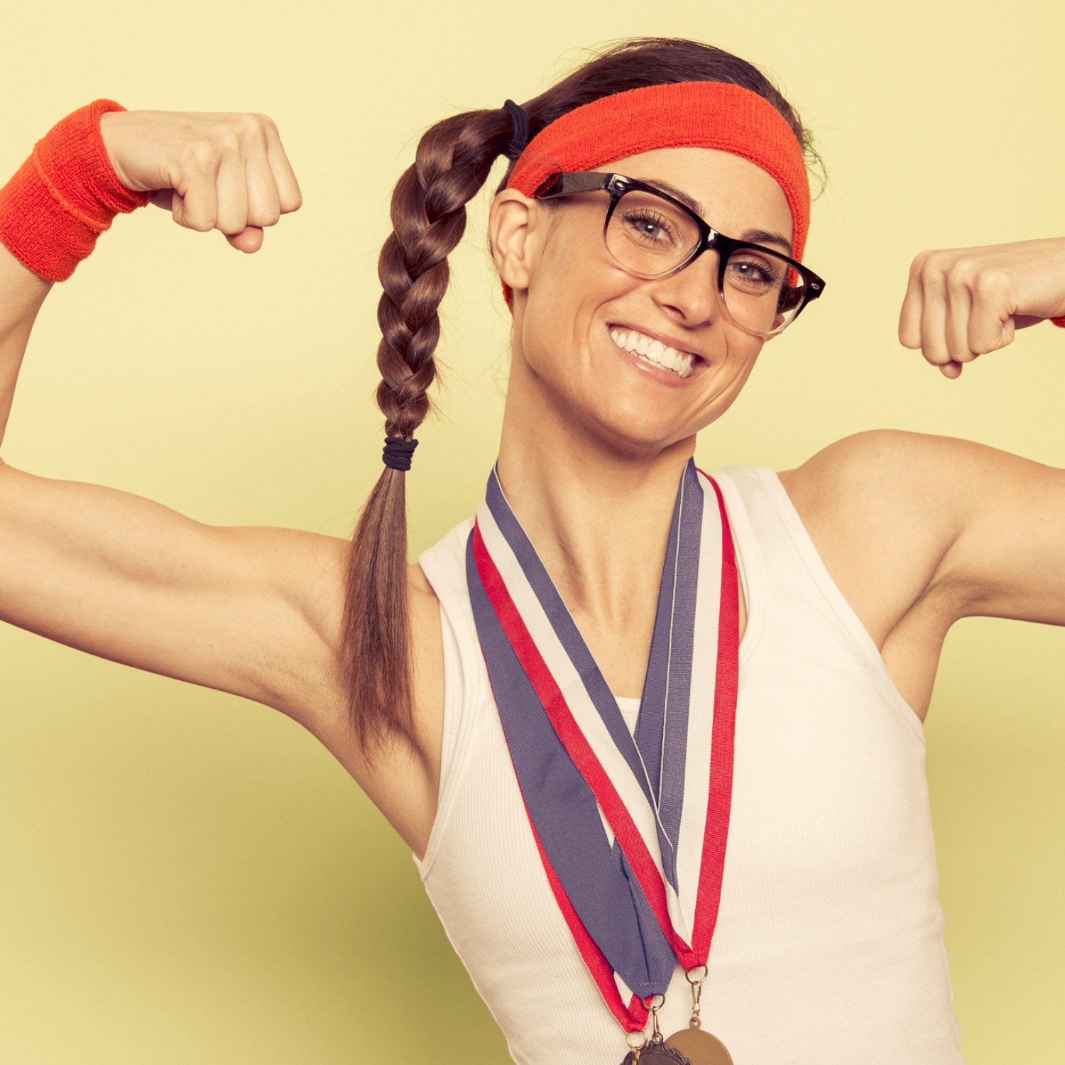 Woman with glassesin workout gear with medals flexing biceps