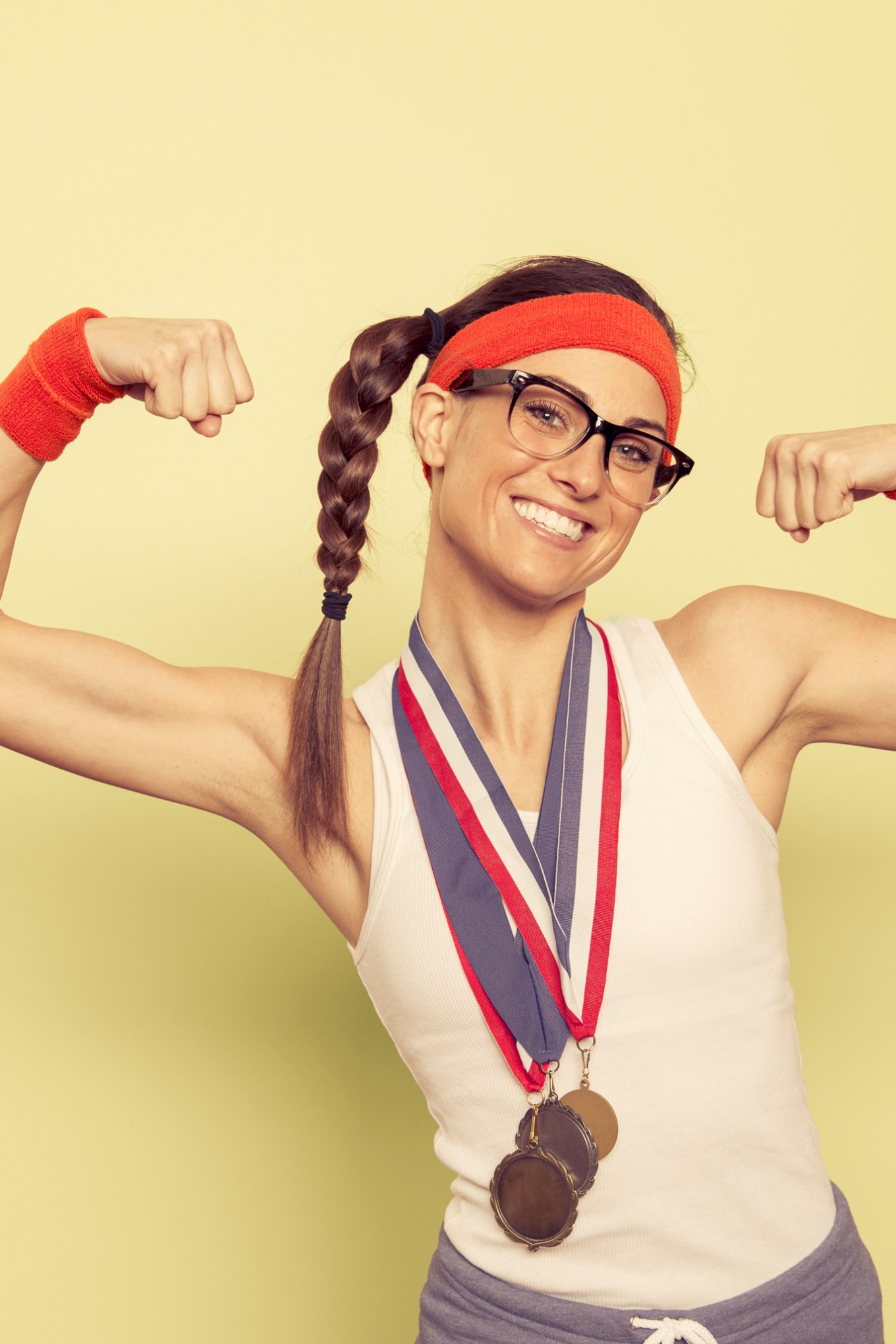 Woman with glassesin workout gear with medals flexing biceps
