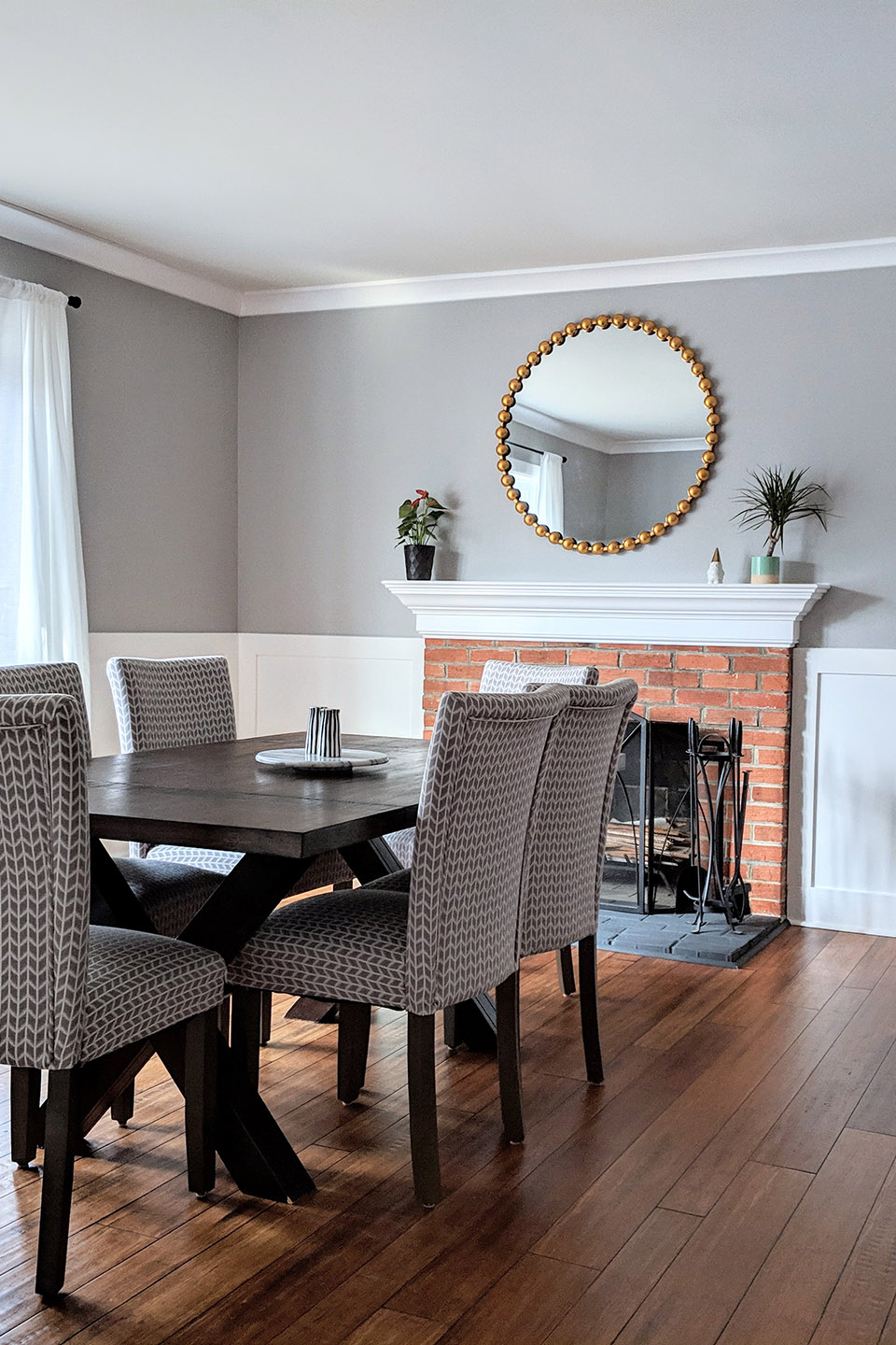 Gray dining room with brick fireplace and circle mirror