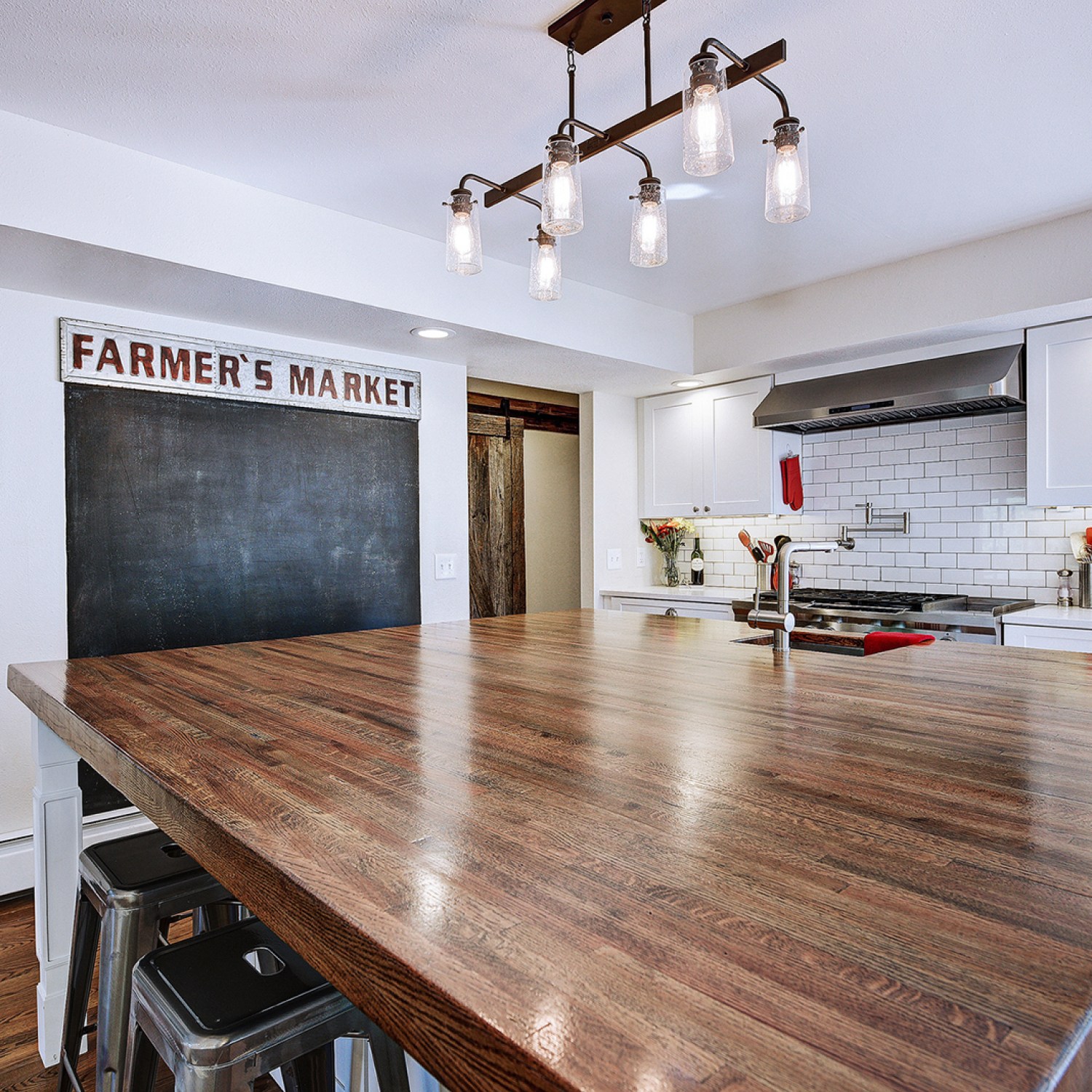 Large wooden kitchen island in front of chalk board