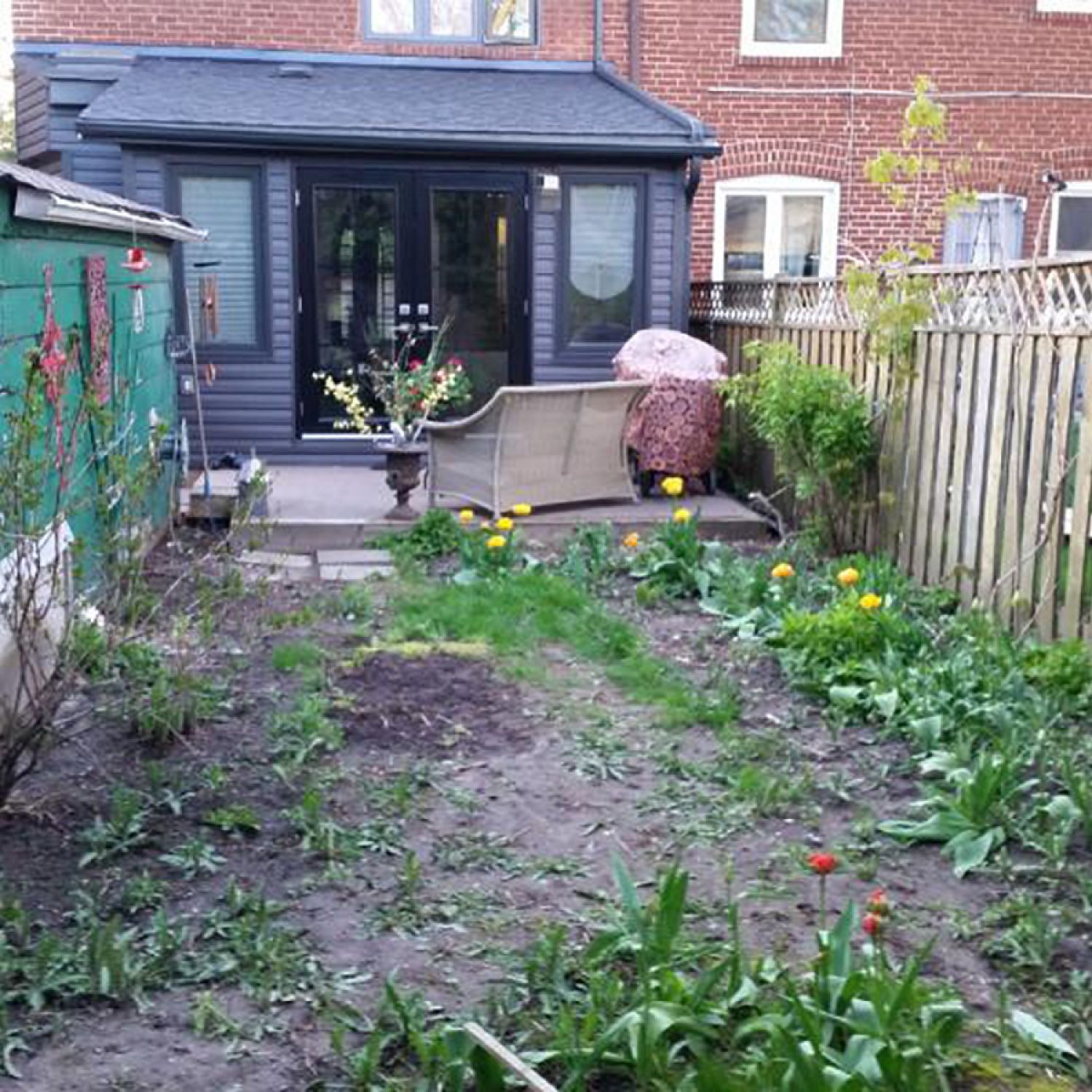 Modest deck and patchy, sparse backyard with weeds