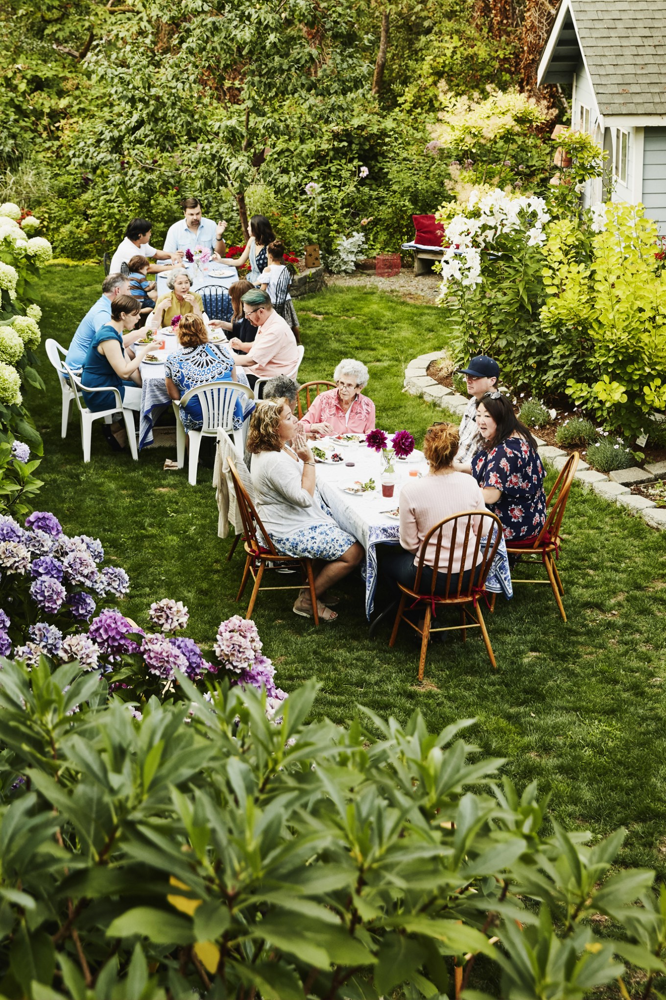 Families gathered at two tables enjoying time in backyard