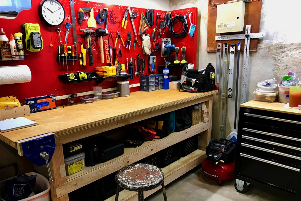 Wooden work bench with red peg board covered in tools