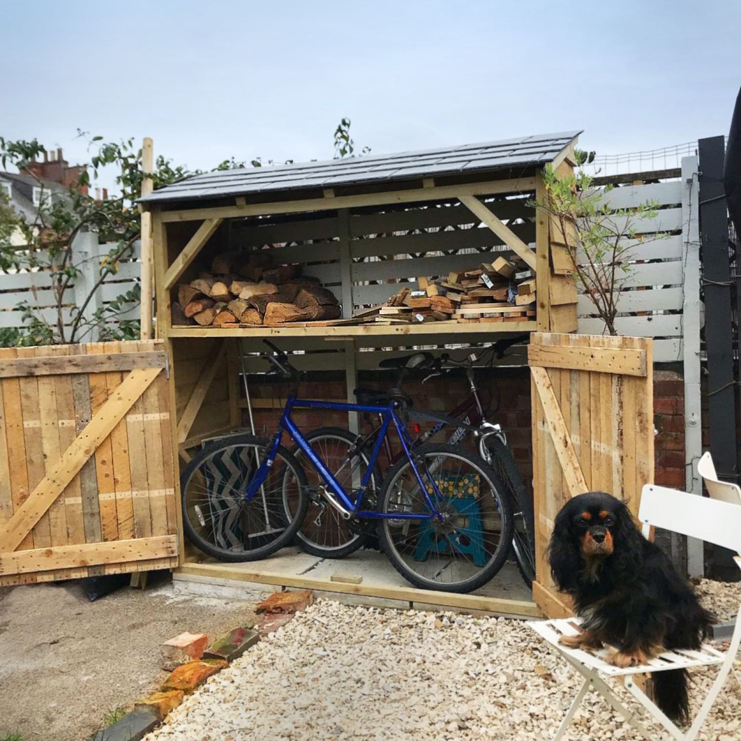 A residential backyard shed designed with areas for storing bikes and firewood.