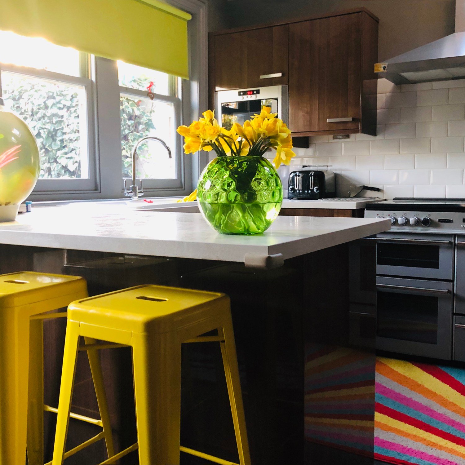Sunny kitchen with neutral countertop and bright yellow tolix stools