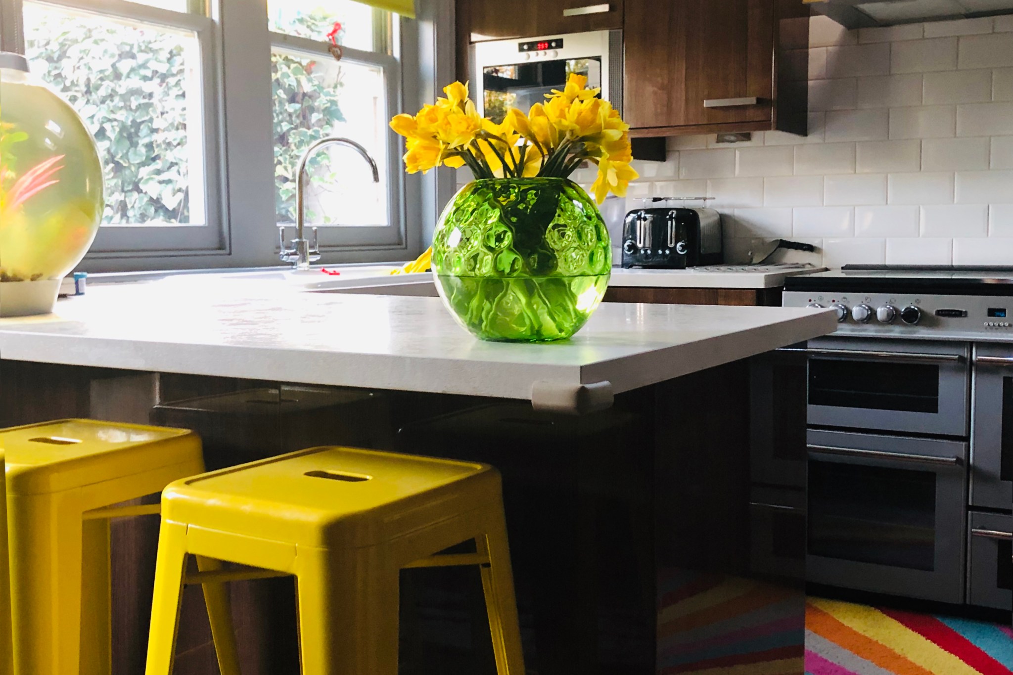Sunny kitchen with neutral countertop and bright yellow tolix stools