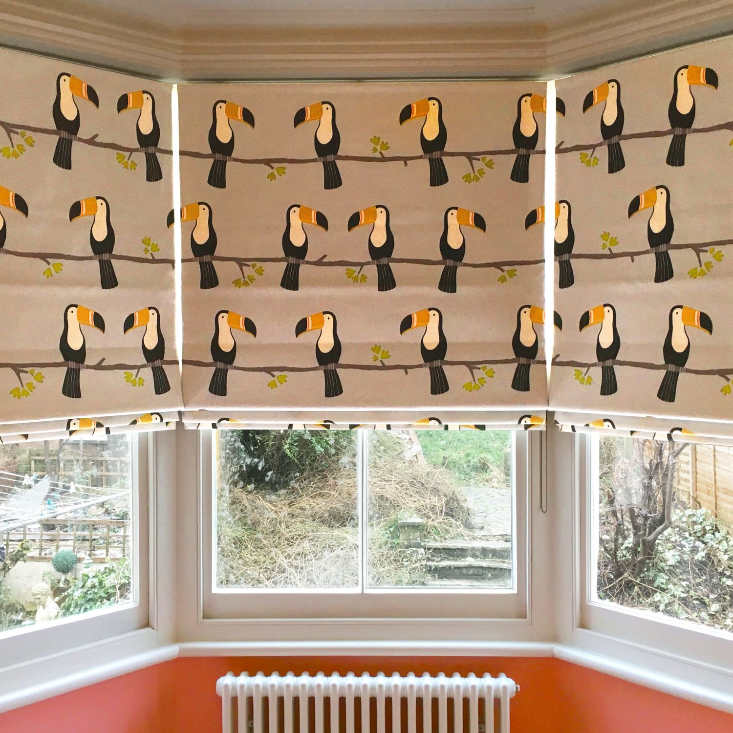 Roman shades in bay window with a toucan print