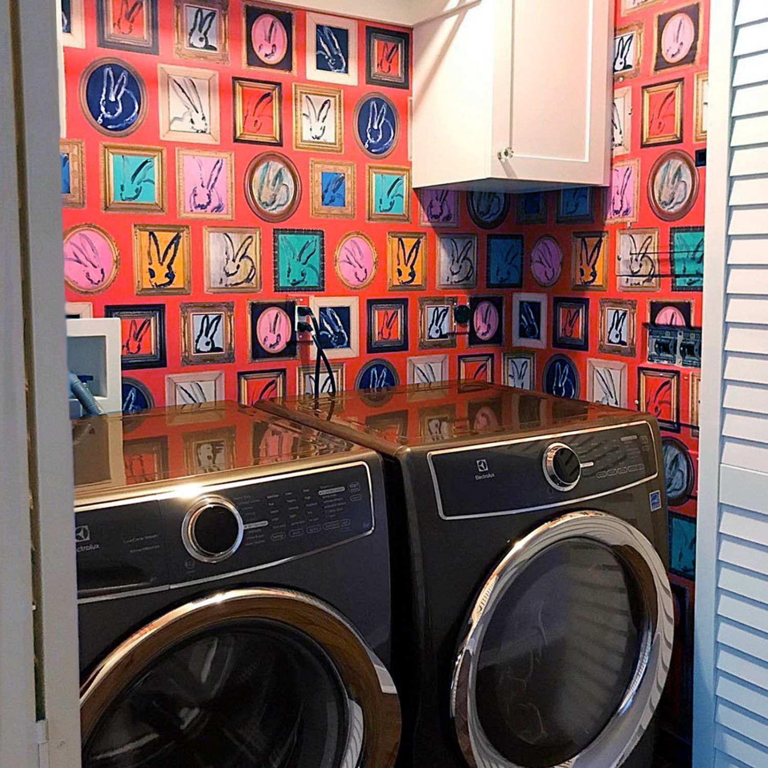 Laundry nook with colorful red wallpaper and bifold door