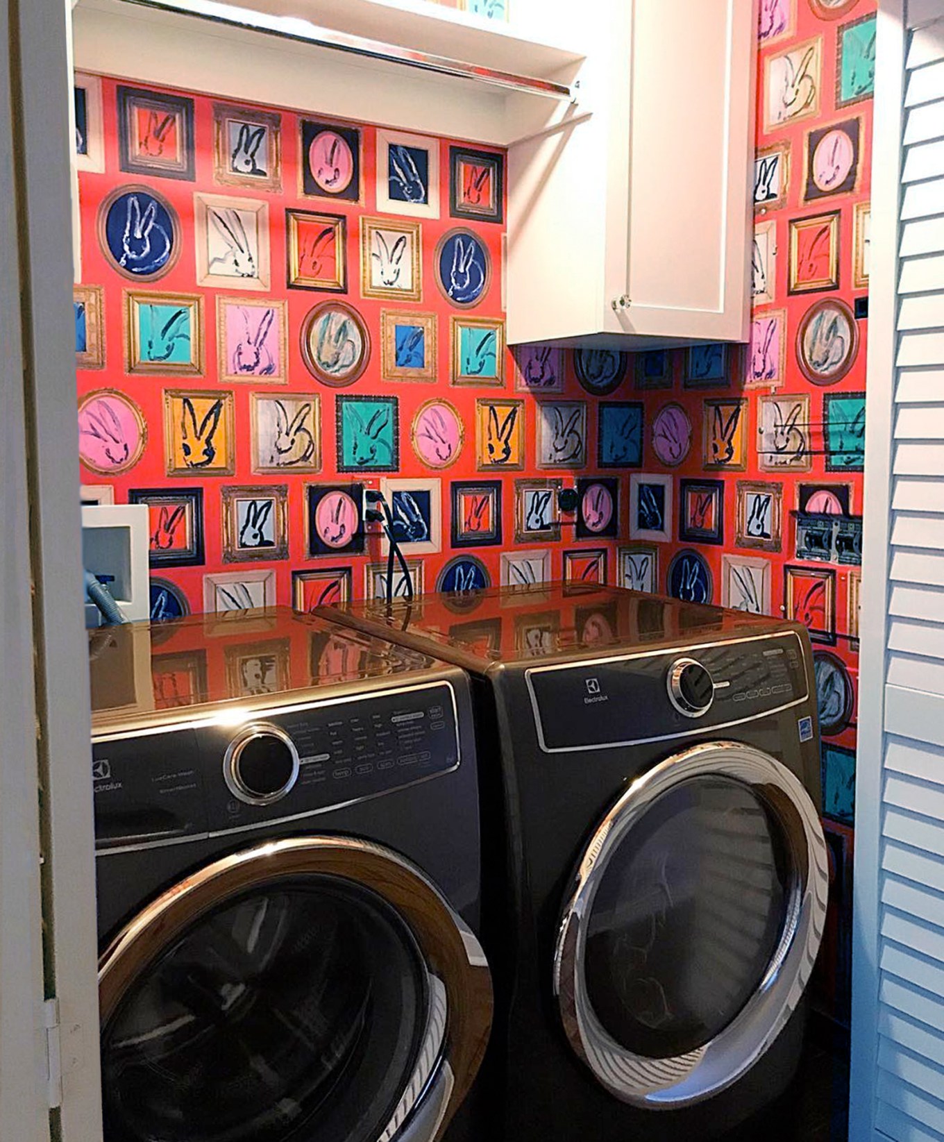 Laundry nook with colorful red wallpaper and bifold door