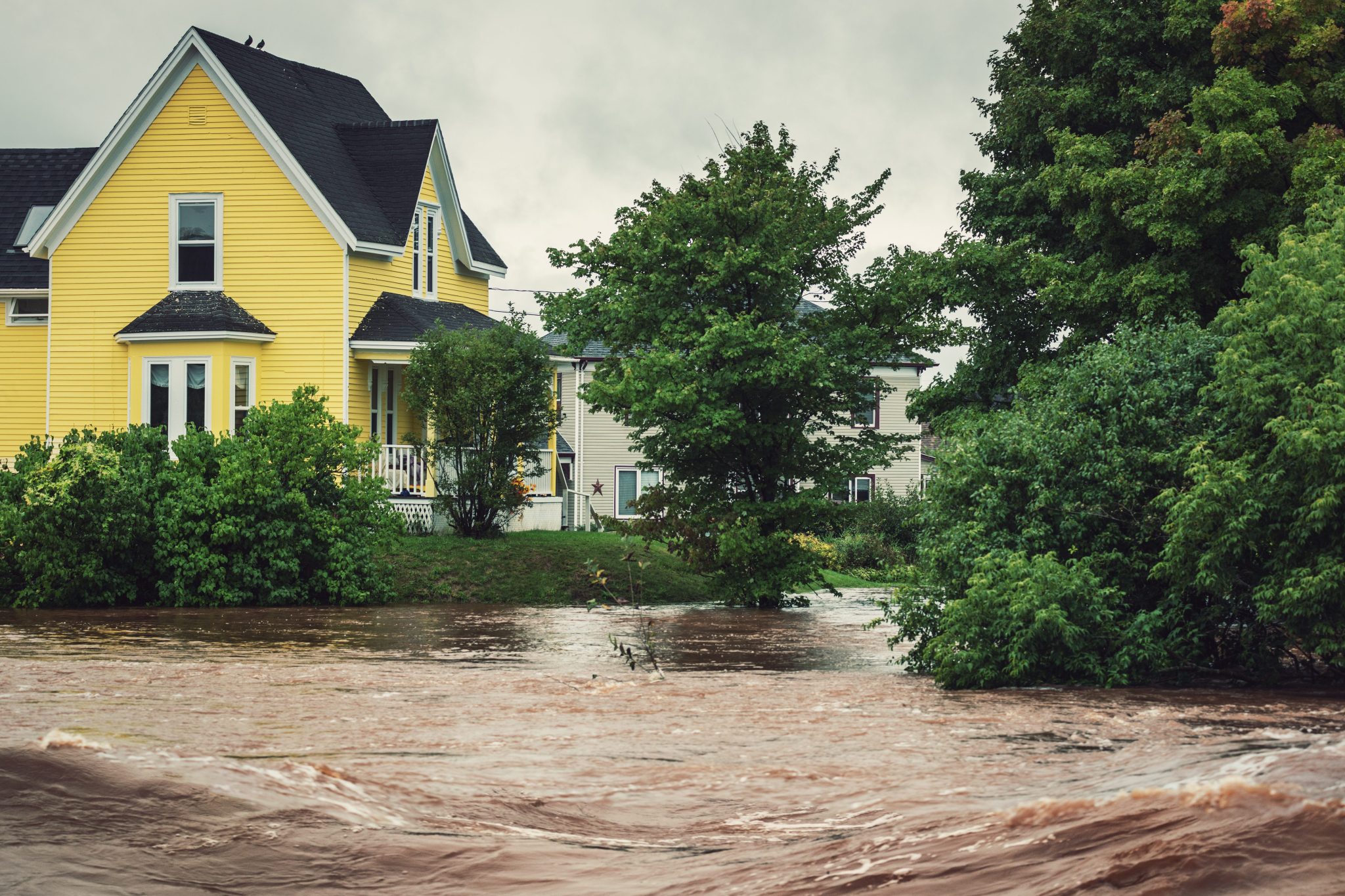 yellow house near a raging river overflowing its banks