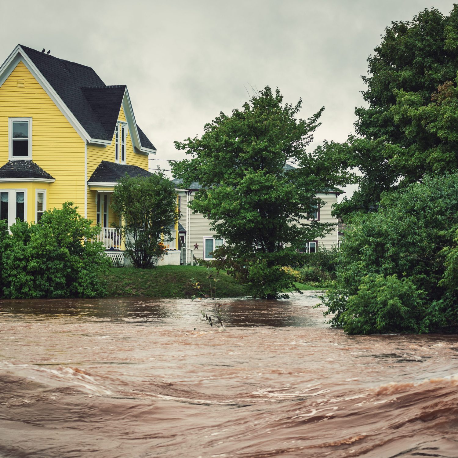 yellow house near a raging river overflowing its banks