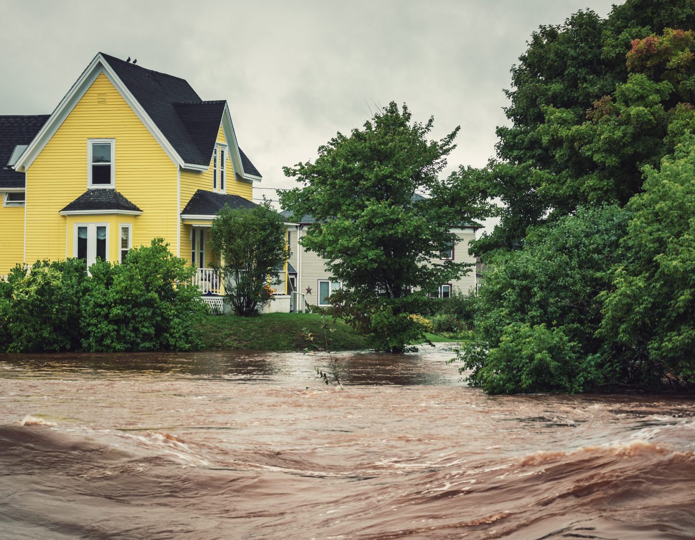 yellow house near a raging river overflowing its banks