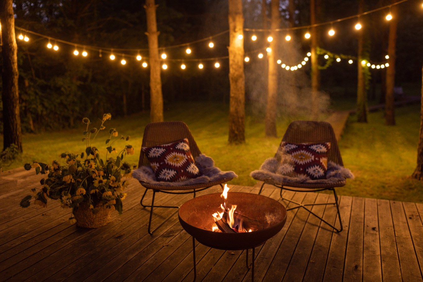 A cozy backyard patio with a fire pit and string lights.