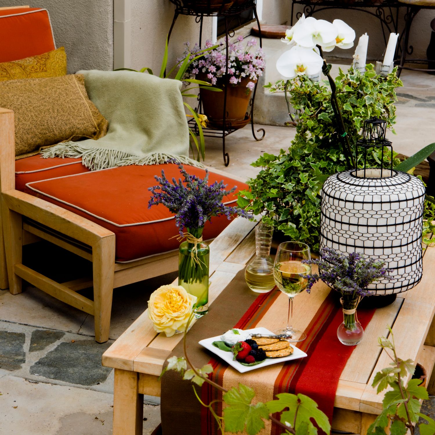 outdoor living space has colorful chair, ottoman and table next to fire pit and lots of plants on patio