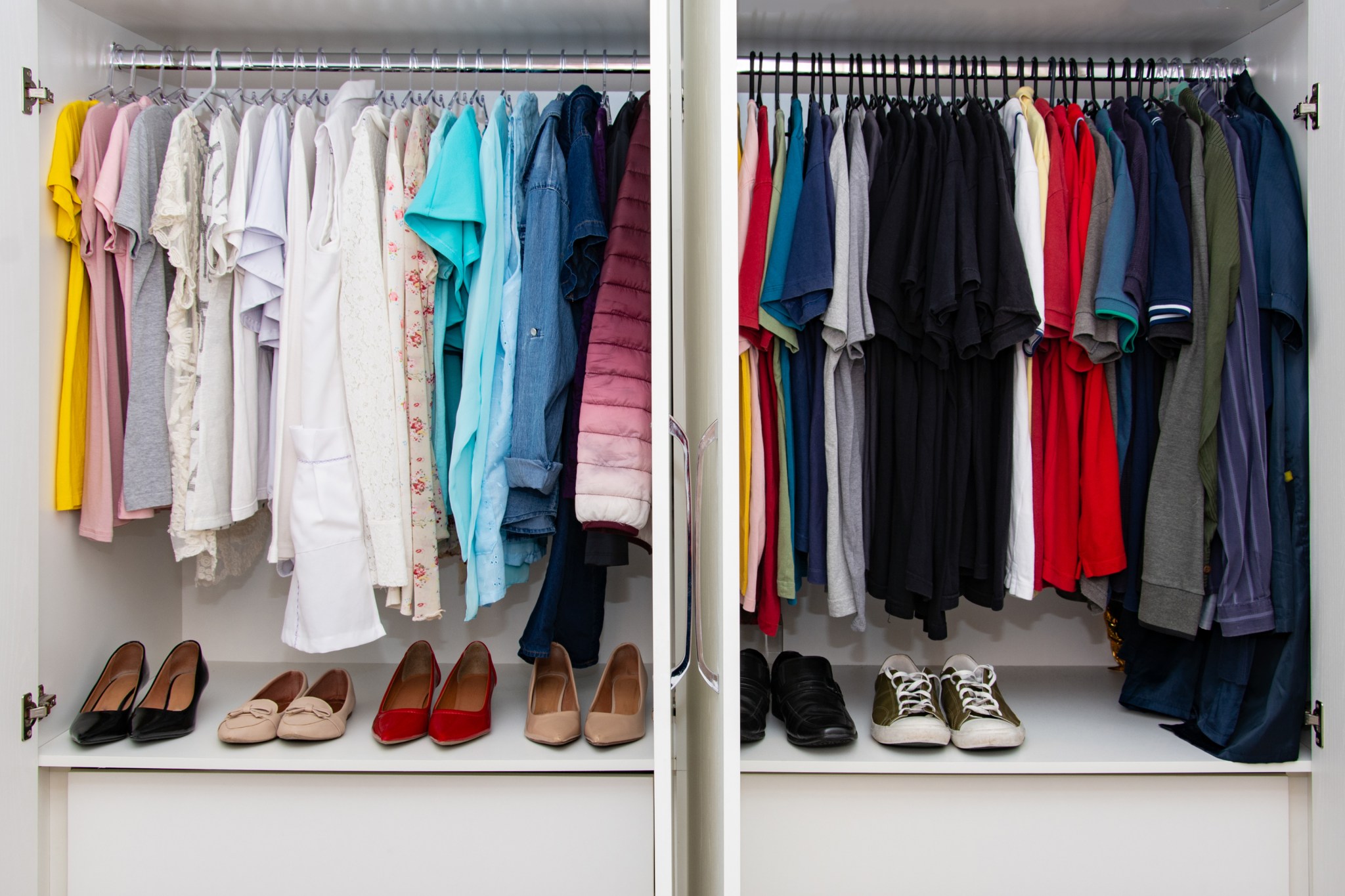 A custom built closet for a married couple with color organized clothing.