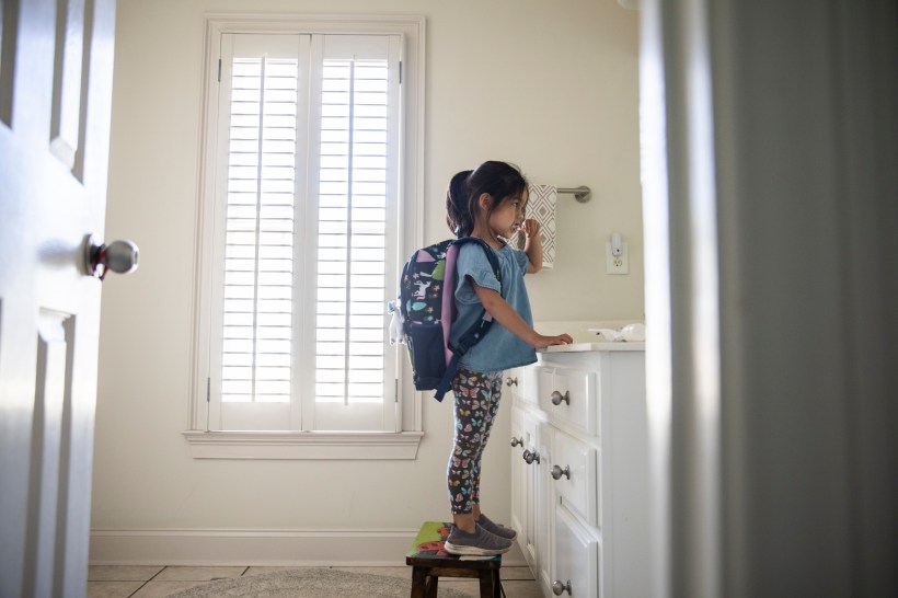 back to school organization kids bathroom your girl with backpack standing on a stool while brushing her teeth at the sink