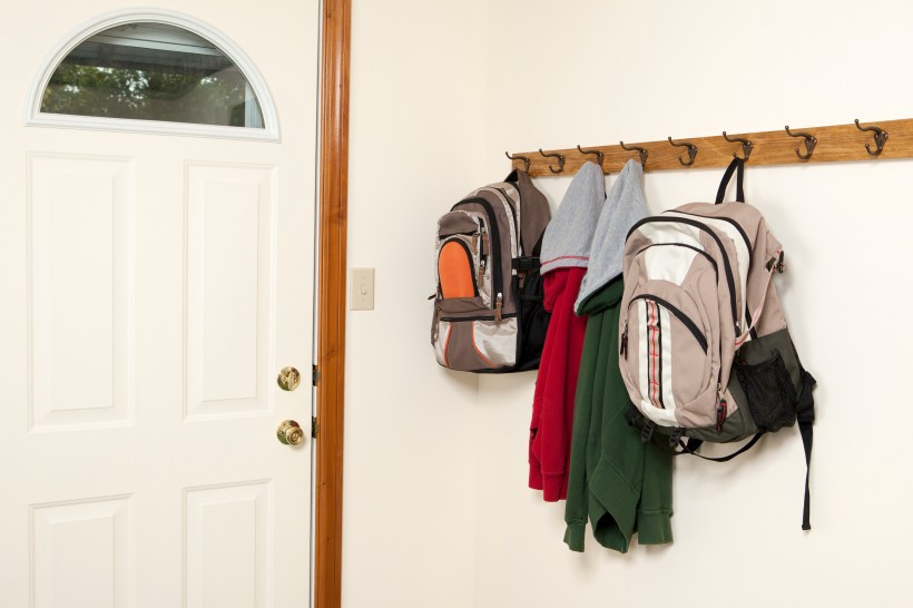 back to school home organization drop zone two backpacks and jackets hanging on a wall rack by the entry door