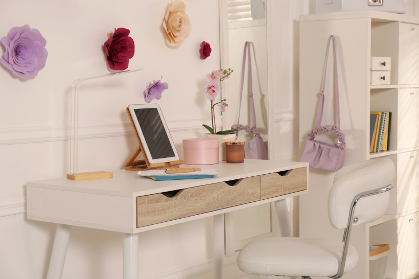 back to school home organization teenager room with a sleek white desk and chair with a tablet and flowers on the wall